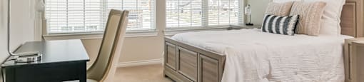A bedroom with a bed, chair, and desk.