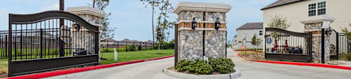 the entrance to a house with a driveway and a gated entrance with two gates