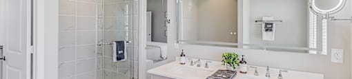 A white bathroom with a glass shower door and a large mirror above the sink.
