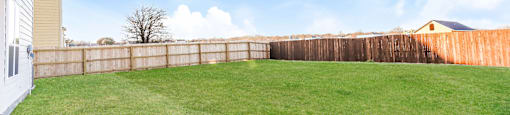 A backyard with a wooden fence and a green lawn.