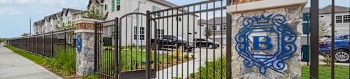 the entrance to a building with a fence and a stone column with a blue logo