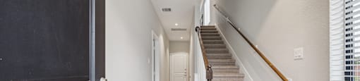 A hallway with a staircase and a black door.