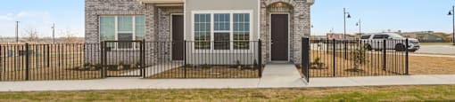 A two-story house with a black fence in front.