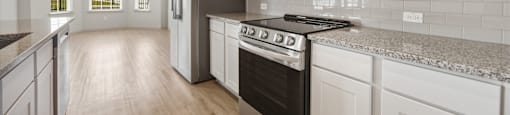 A modern kitchen with white cabinets and a black stove top oven.