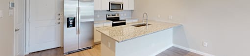 a kitchen with white cabinets and a counter top and a refrigerator