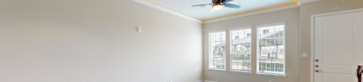 an empty living room with white walls and a ceiling fan
