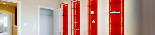 a glass table in the center of a room with four red mirrors on the wall