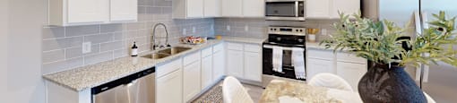 a kitchen with white cabinets and a table with white chairs