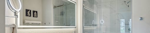 A white bathroom with a glass shower stall and a white sink vanity.