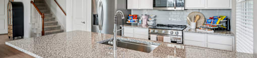 A kitchen with granite countertops and white cabinets.