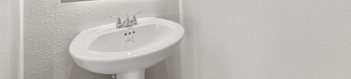 A white sink in a bathroom with a mirror above it.