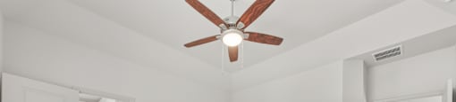 A room with a ceiling fan and carpeted floor.