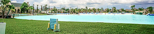 a lounge chair sits on the grass in front of a large blue pool with people in it