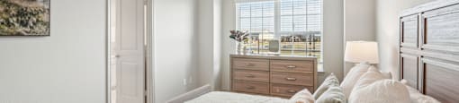 A bedroom with a bed, a ceiling fan, and a window with blinds.