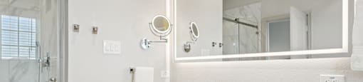 A white bathroom with a sink, mirror, and shower.
