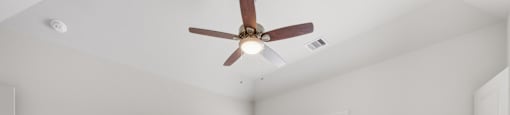 A room with a ceiling fan and carpeted floor.
