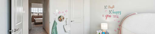 A child's bedroom with a bed, nightstand, and a wall decal that says