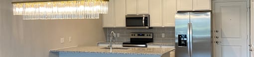 a kitchen with a large island and a stainless steel refrigerator