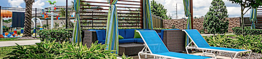 a gazebo with blue lounge chairs and curtains