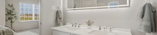 A bathroom with a white vanity and a large mirror.