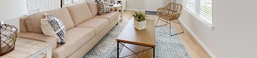 A living room with a beige couch, a wooden coffee table, and a ceiling fan.