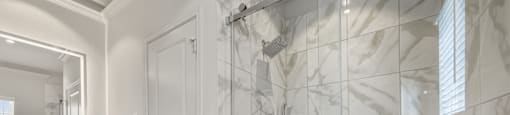 A bathroom with a white sink and a glass shower stall.