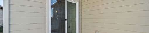A patio with a sliding glass door and a white wall.