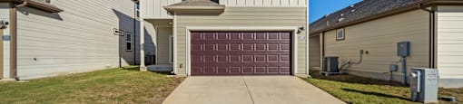 A two-story house with a garage door in the middle.