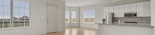 A spacious living room with a ceiling fan and hardwood floors.