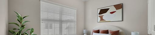 A bedroom with a large bed and a potted plant.