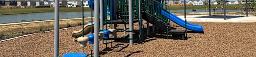 A playground with a blue slide and a brown sandy area.