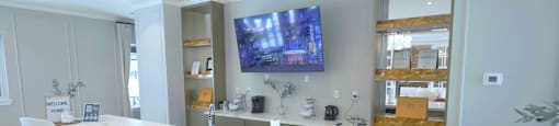 A modern kitchen with a bar area and a television mounted above the island.