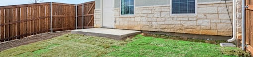 A house with a brown fence and a green lawn.