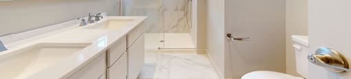 A white bathroom with a marble floor and a walk-in shower.