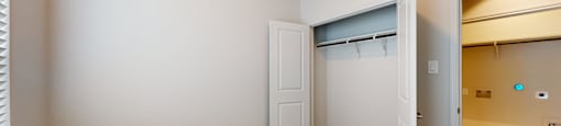 A room with a carpeted floor and a closet with a door open.