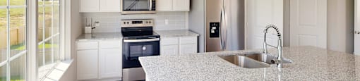 A kitchen with a granite countertop and stainless steel appliances.