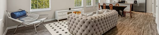 A modern living room with a grey tufted sofa and a wooden floor.