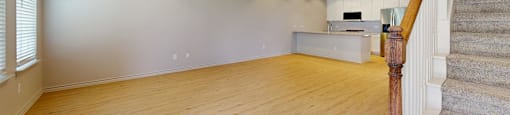 A room with a staircase on the right side and a ceiling fan on the left.