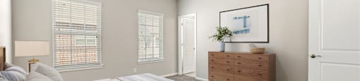 A bedroom with a bed, dresser, and window.