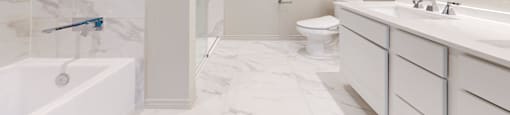 A white bathroom with a marble floor and a glass shower stall.