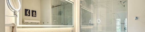 A white bathroom with a glass shower stall and a white sink.