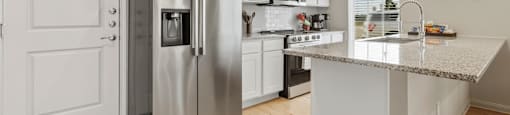 A modern kitchen with a stainless steel refrigerator and white cabinets.