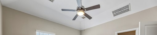 A room with a ceiling fan and carpeted floor.