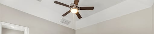A room with a ceiling fan and carpeted floor.