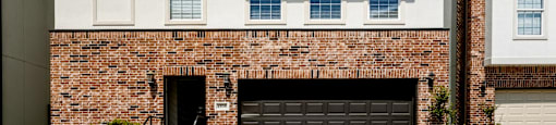 A two-story building with a brick facade and a black garage door.