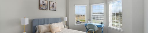 A bedroom with a large bed and a view of the street through the window.