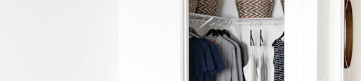 a closet filled with clothes and shoes in a living room