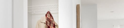 a hallway with a white door and a robe hanging on the wall