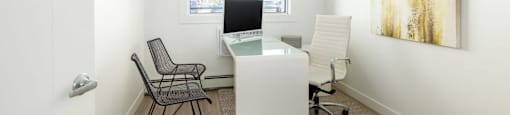 an office with a desk and two chairs and a window