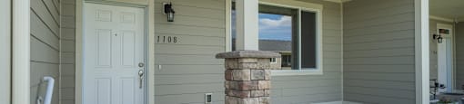 A house with a white door and a stone pillar.